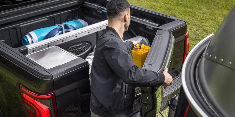 A photo of a man placing a toolbox in the bed of a 2024 Ford F-150